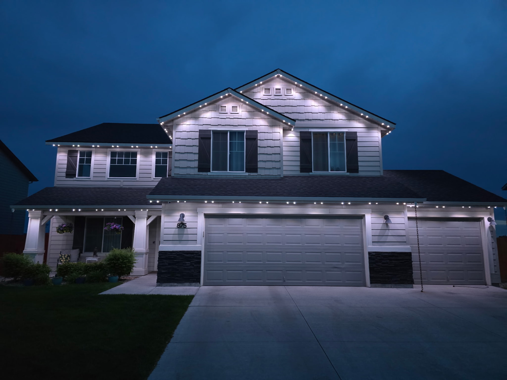 Two-story home in cool pure white permanent roofline lighting at night