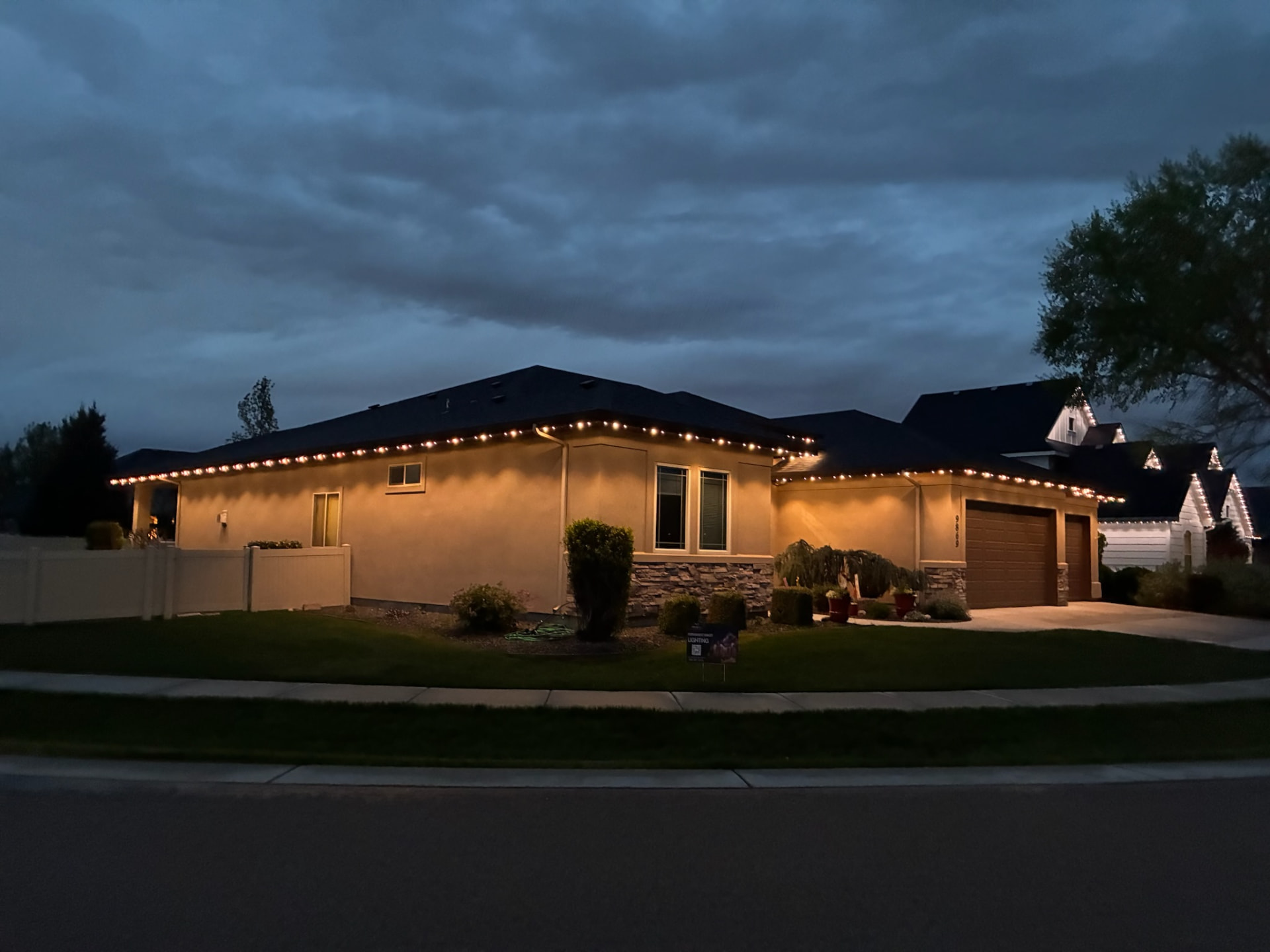 Single-story home with warm white permanent roofline lighting at dusk