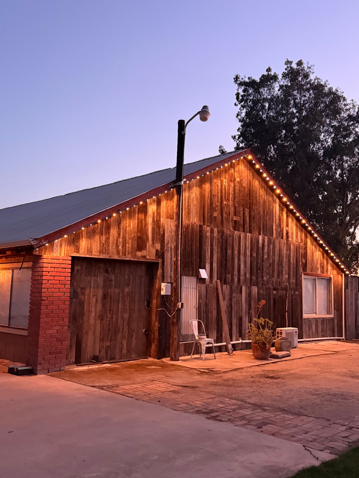 Rustic wooden barn with warm white permanent LED lighting along the roofline at dusk